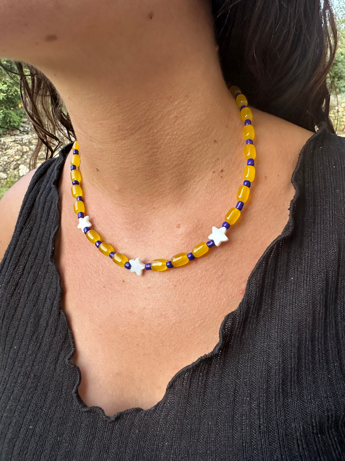 Collar hecho a mano con cuentas de cerámica amarillas, cuentas azules y con 4 estrellas de nácar. Cierre ajustable de acero inoxidable