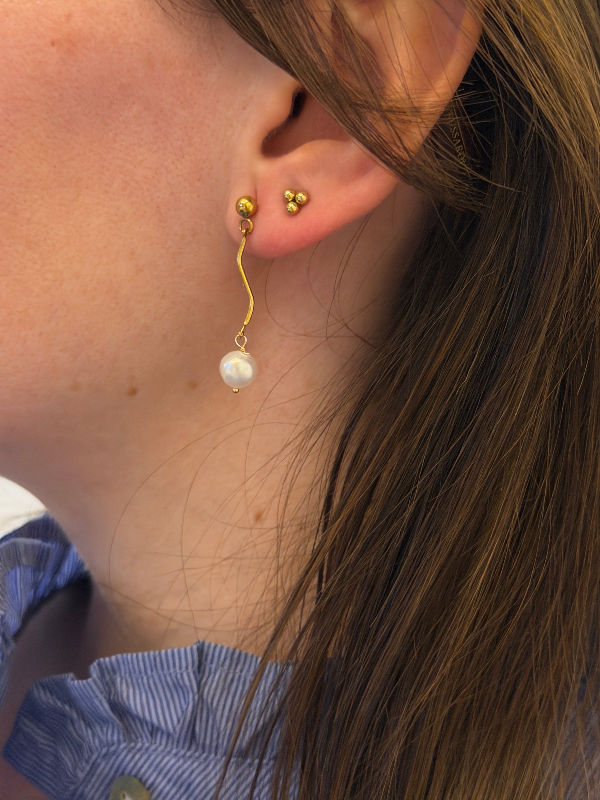 Pendientes de acero inoxidable en color dorado con onda y una perla. Estos pendientes son perfectos para elevar tus looks. 