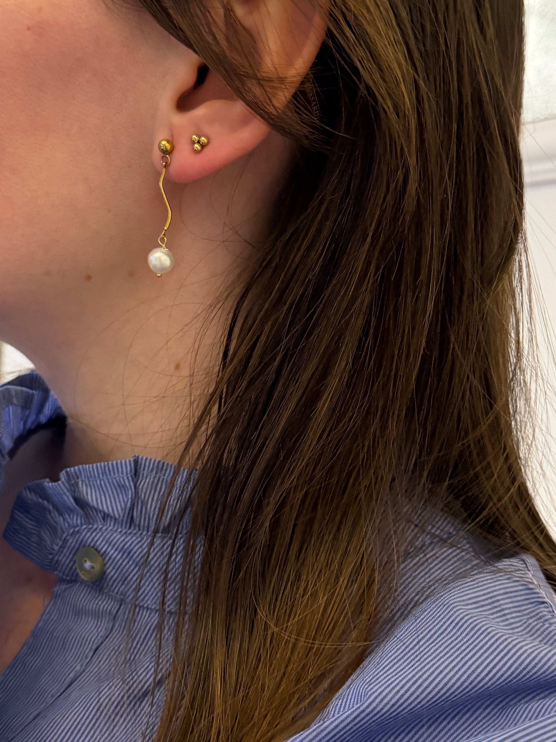 Pendientes de acero inoxidable en color dorado con onda y una perla. Estos pendientes son perfectos para elevar tus looks. 