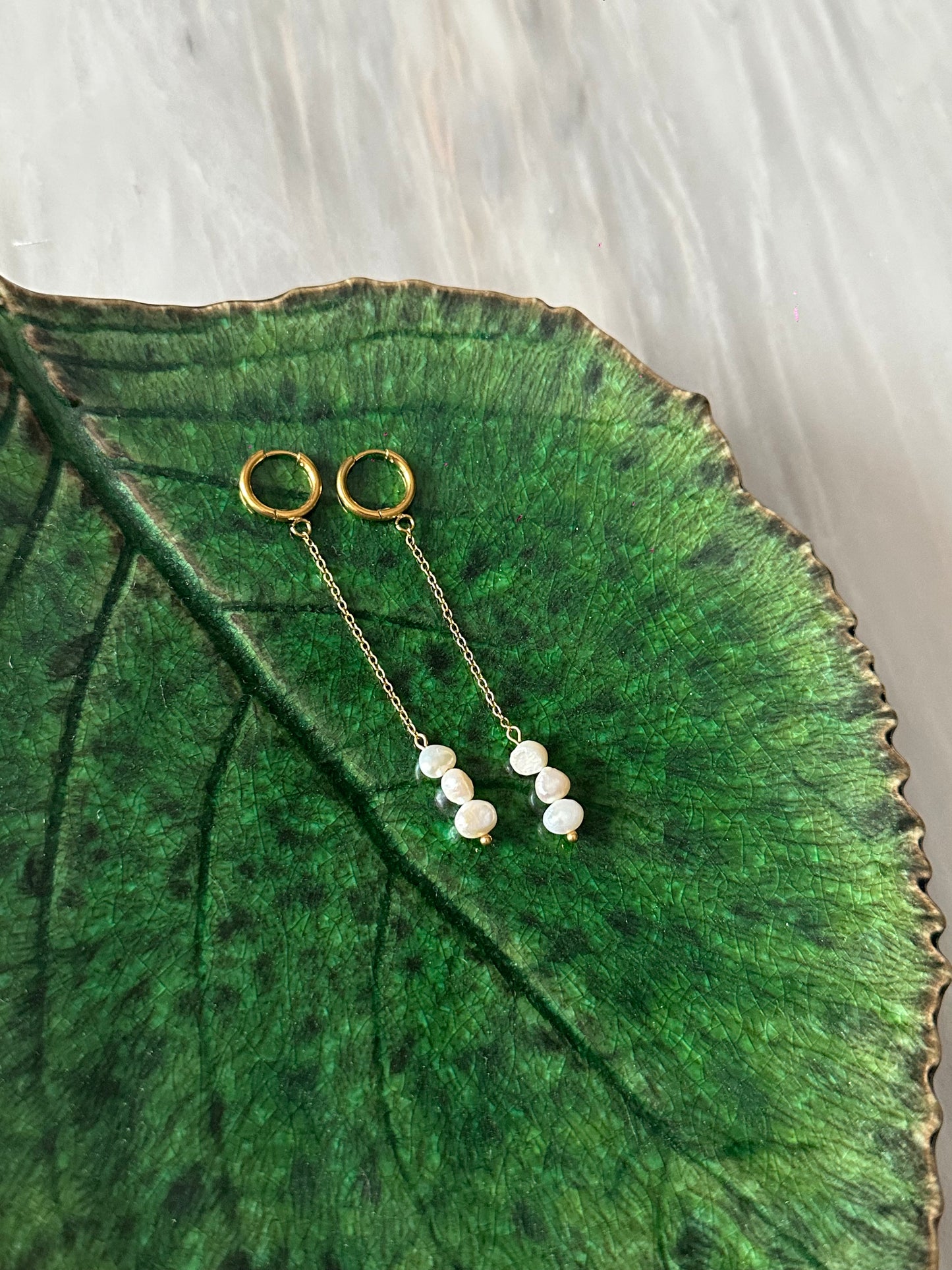 Pendientes de acero inoxidable en color dorado largos con tres perlas. Estos pendientes son perfectos para elevar tus looks. 