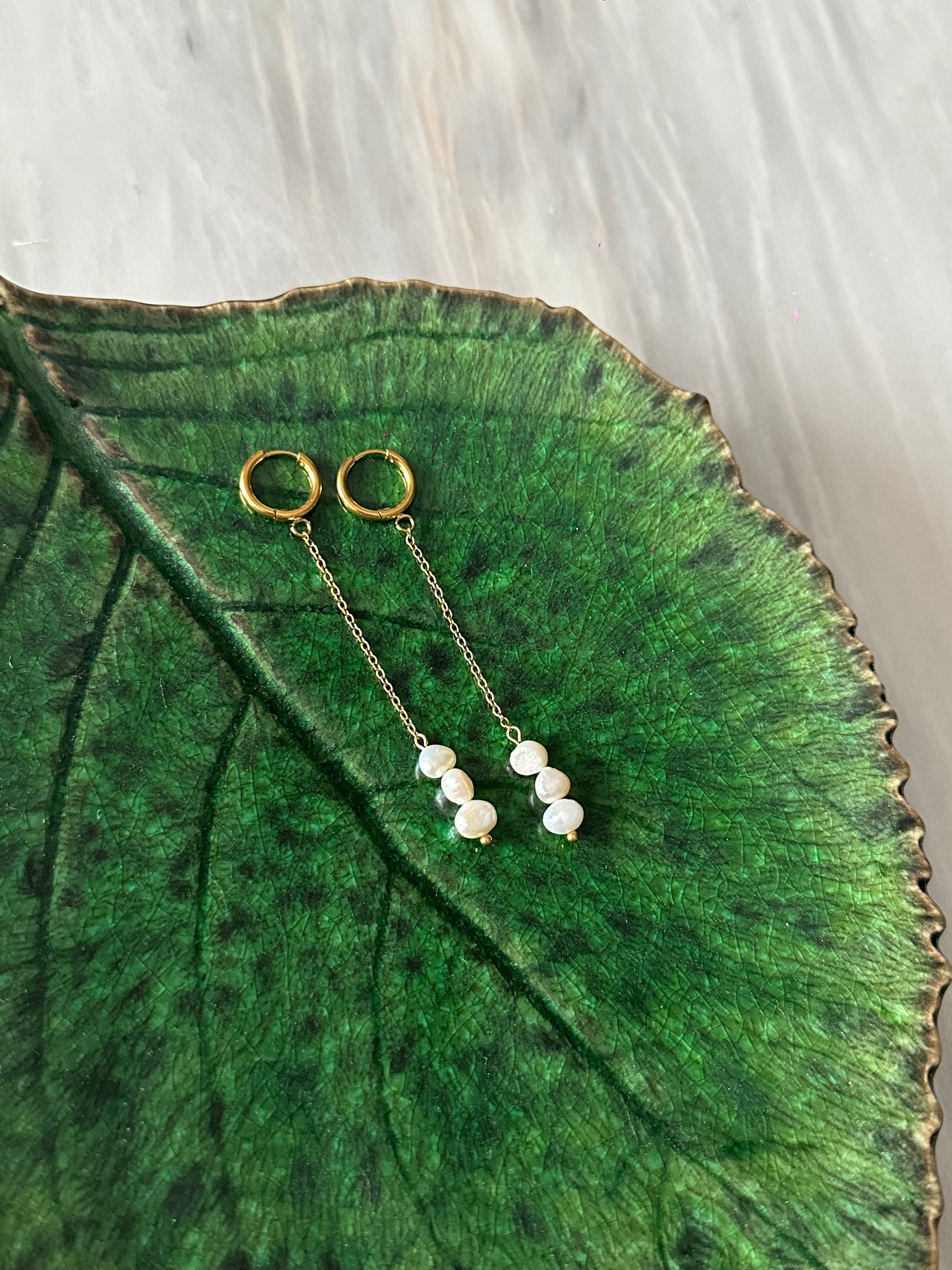 Pendientes de acero inoxidable en color dorado largos con tres perlas. Estos pendientes son perfectos para elevar tus looks. 