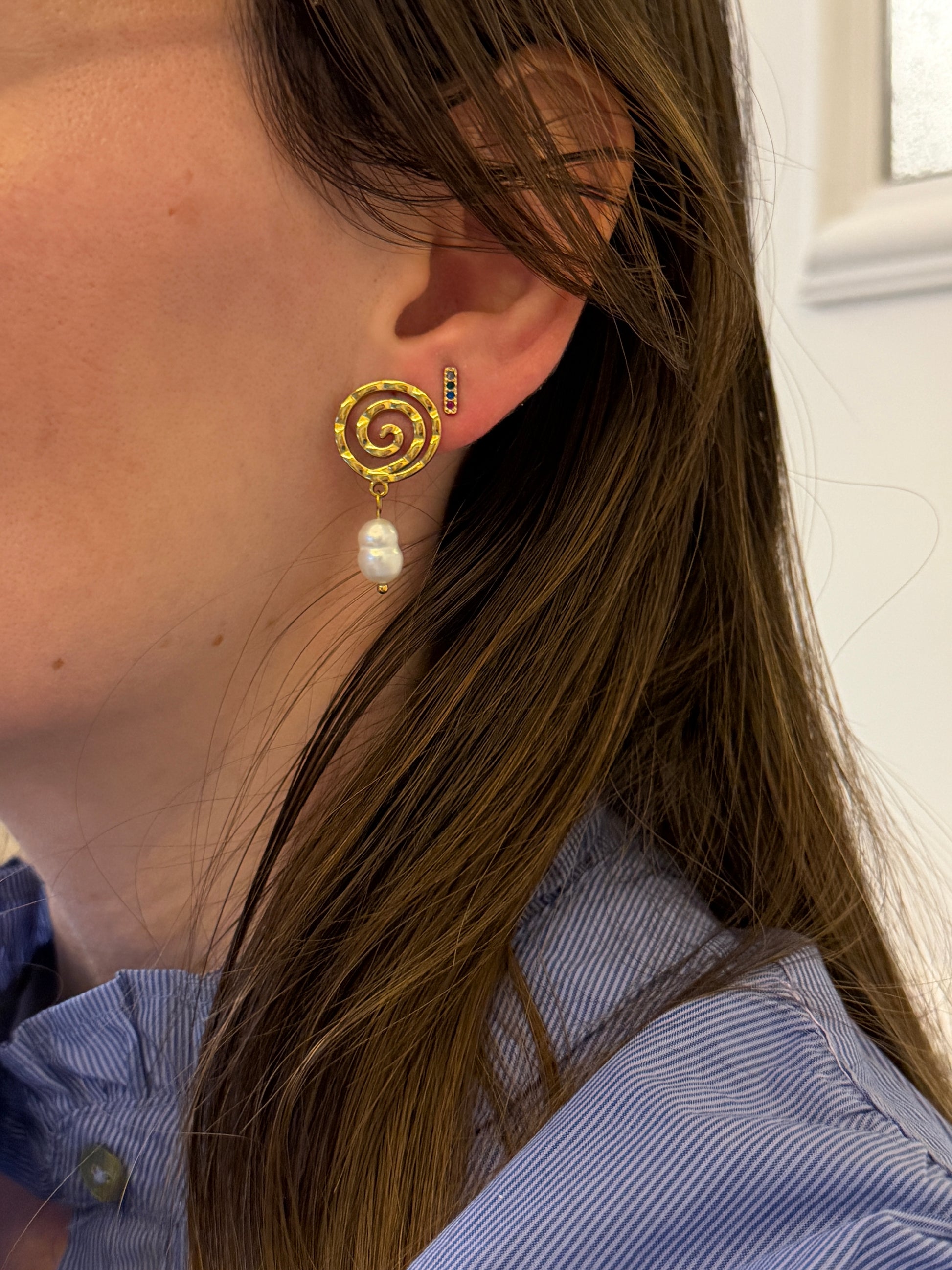Pendientes de acero inoxidable en color plateado con espiral y una perla. Estos pendientes son perfectos para elevar tus looks. 
