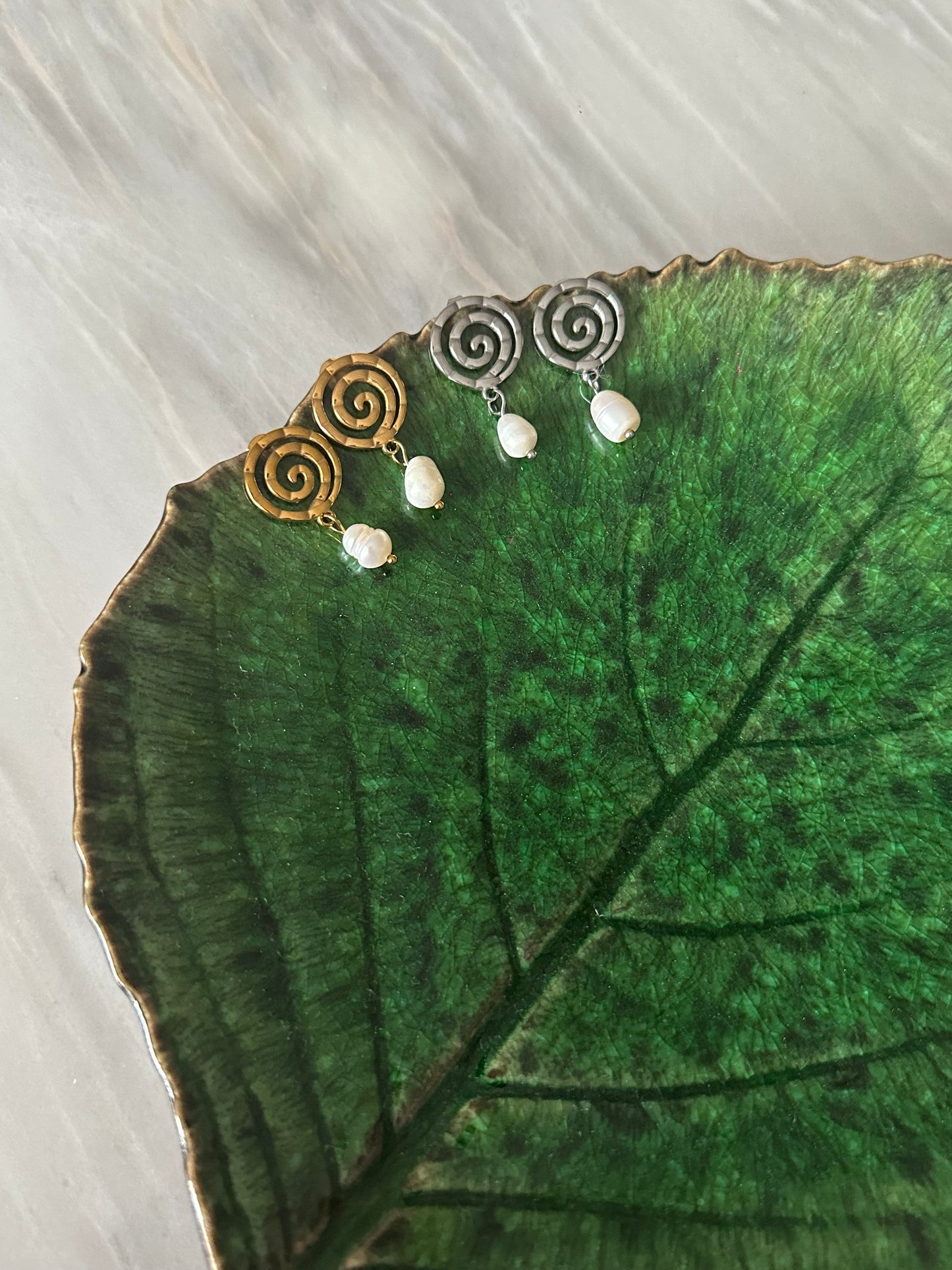 Pendientes de acero inoxidable en color plateado con espiral y una perla. Estos pendientes son perfectos para elevar tus looks. 