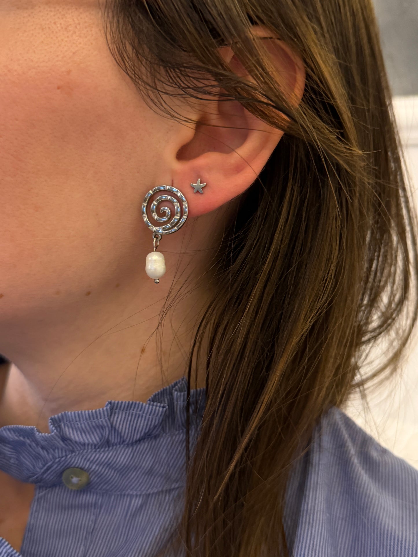 Pendientes de acero inoxidable en color plateado con espiral y una perla. Estos pendientes son perfectos para elevar tus looks. 