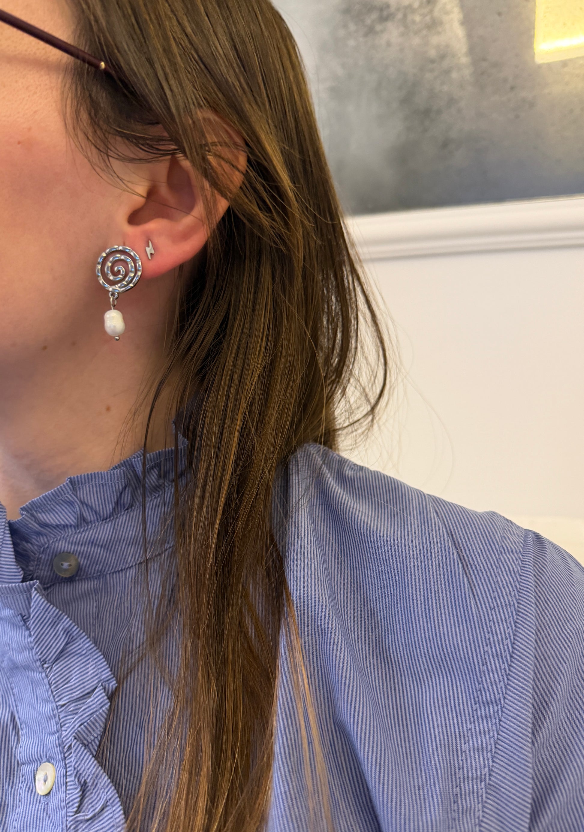 Pendientes de acero inoxidable en color plateado con espiral y una perla. Estos pendientes son perfectos para elevar tus looks. 