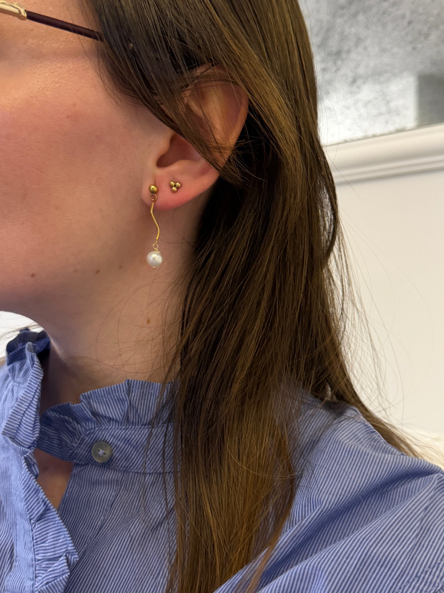 Pendientes de acero inoxidable en color dorado con onda y una perla. Estos pendientes son perfectos para elevar tus looks. 