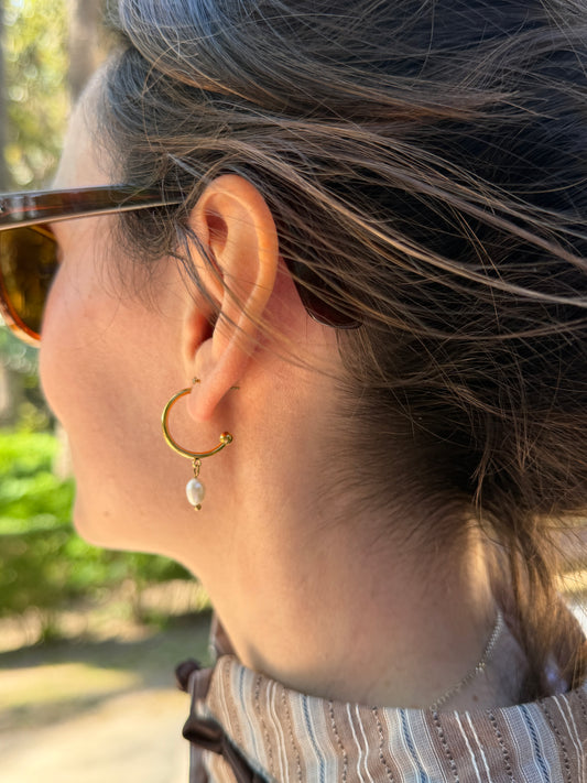 Pendientes de aro de acero inoxidable en color dorado con perla de río colgando. Estos pendientes son perfectos para elevar tus looks. 