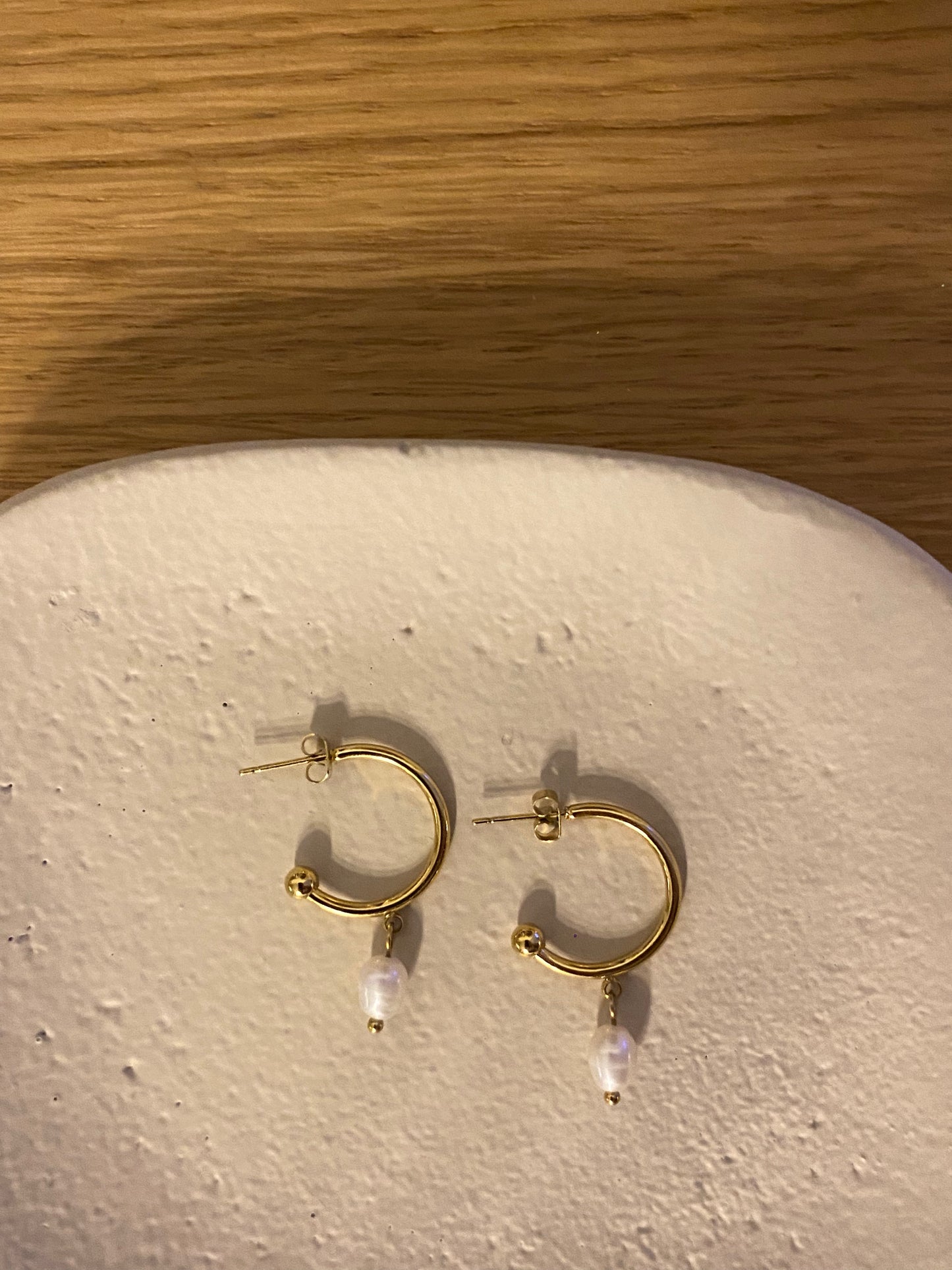 Pendientes de aro de acero inoxidable en color dorado con perla de río colgando. Estos pendientes son perfectos para elevar tus looks. 