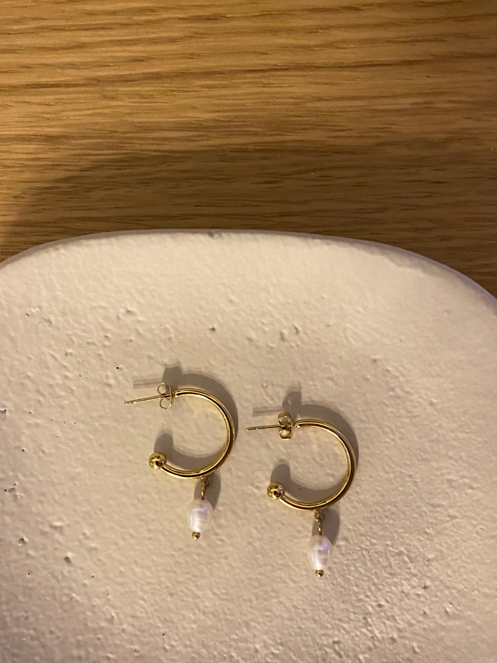 Pendientes de aro de acero inoxidable en color dorado con perla de río colgando. Estos pendientes son perfectos para elevar tus looks. 
