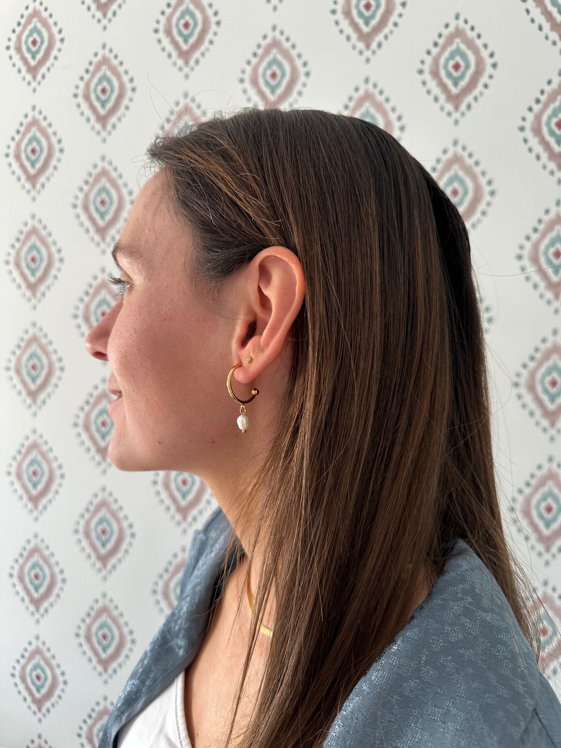 Pendientes de aro de acero inoxidable en color dorado con perla de río colgando. Estos pendientes son perfectos para elevar tus looks. 