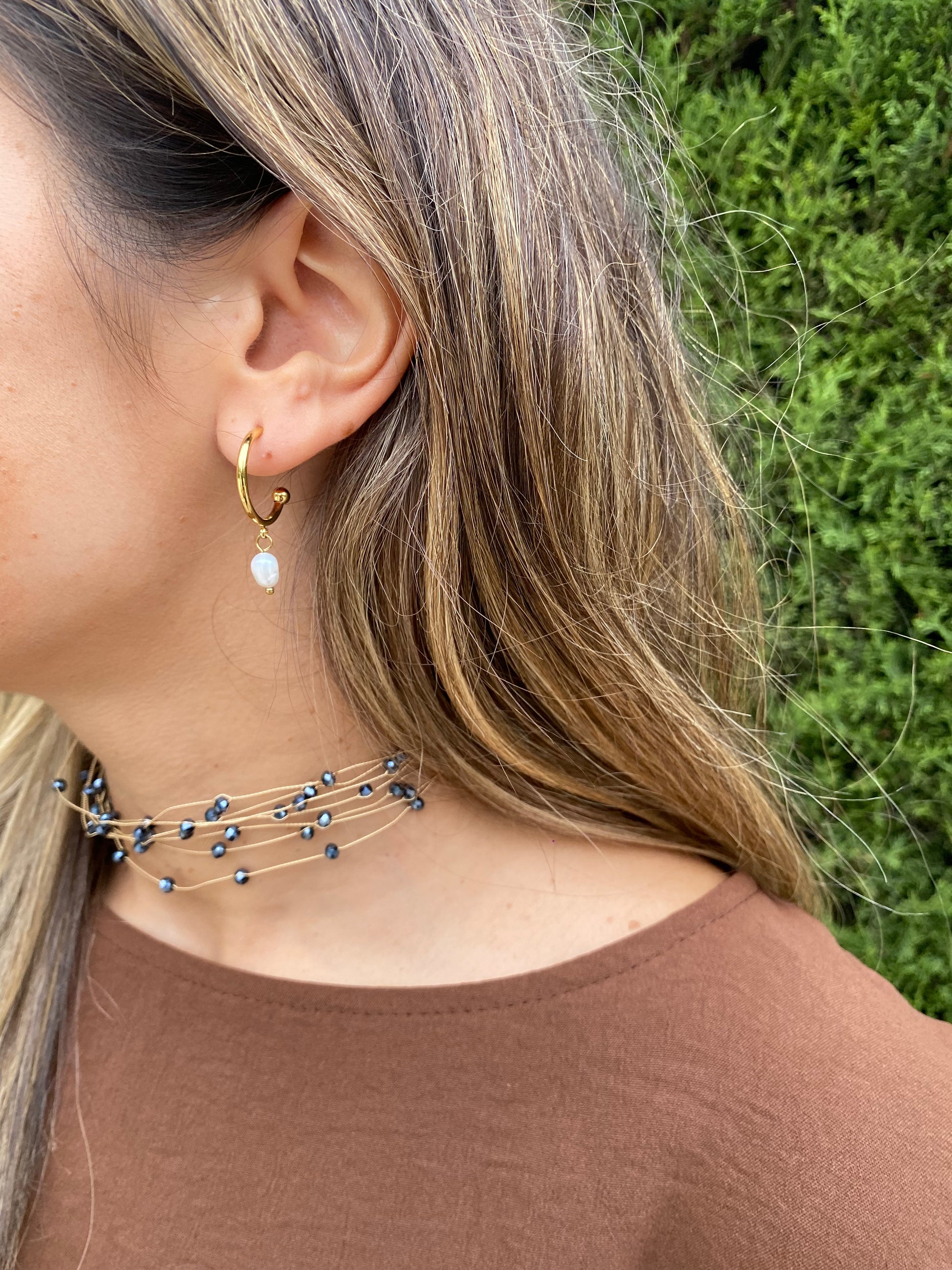 Pendientes de aro de acero inoxidable en color dorado con perla de río colgando. Estos pendientes son perfectos para elevar tus looks. 