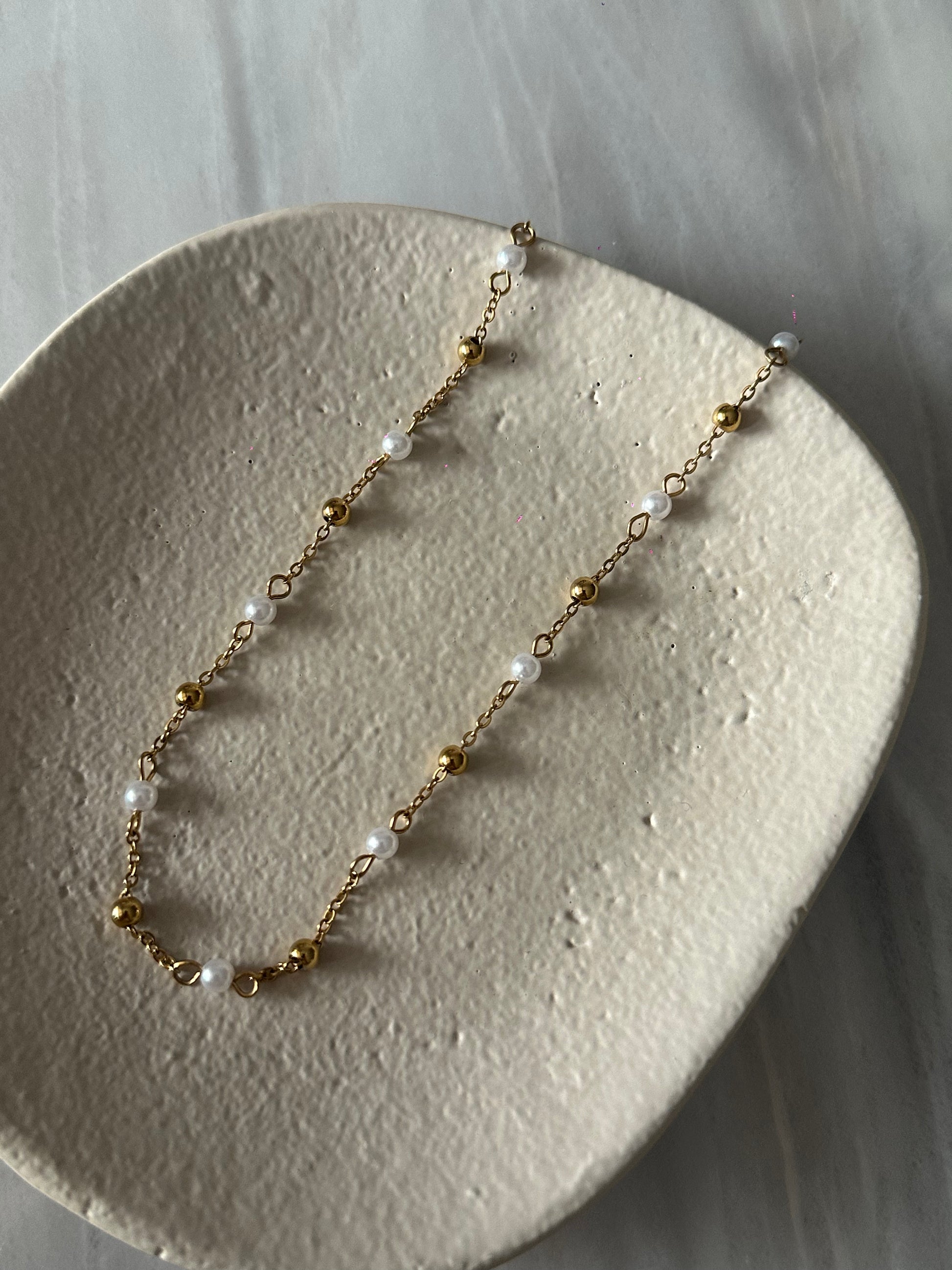 Collar de acero inoxidable en color oro con perla de río. Es ajustable e hipoalergénico.