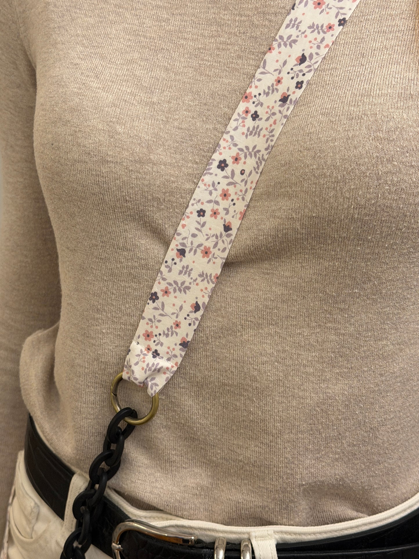 Cuelgamóvil con tela con flores y eslabones negros. Ajustable y con arandelas de acero inoxidable.