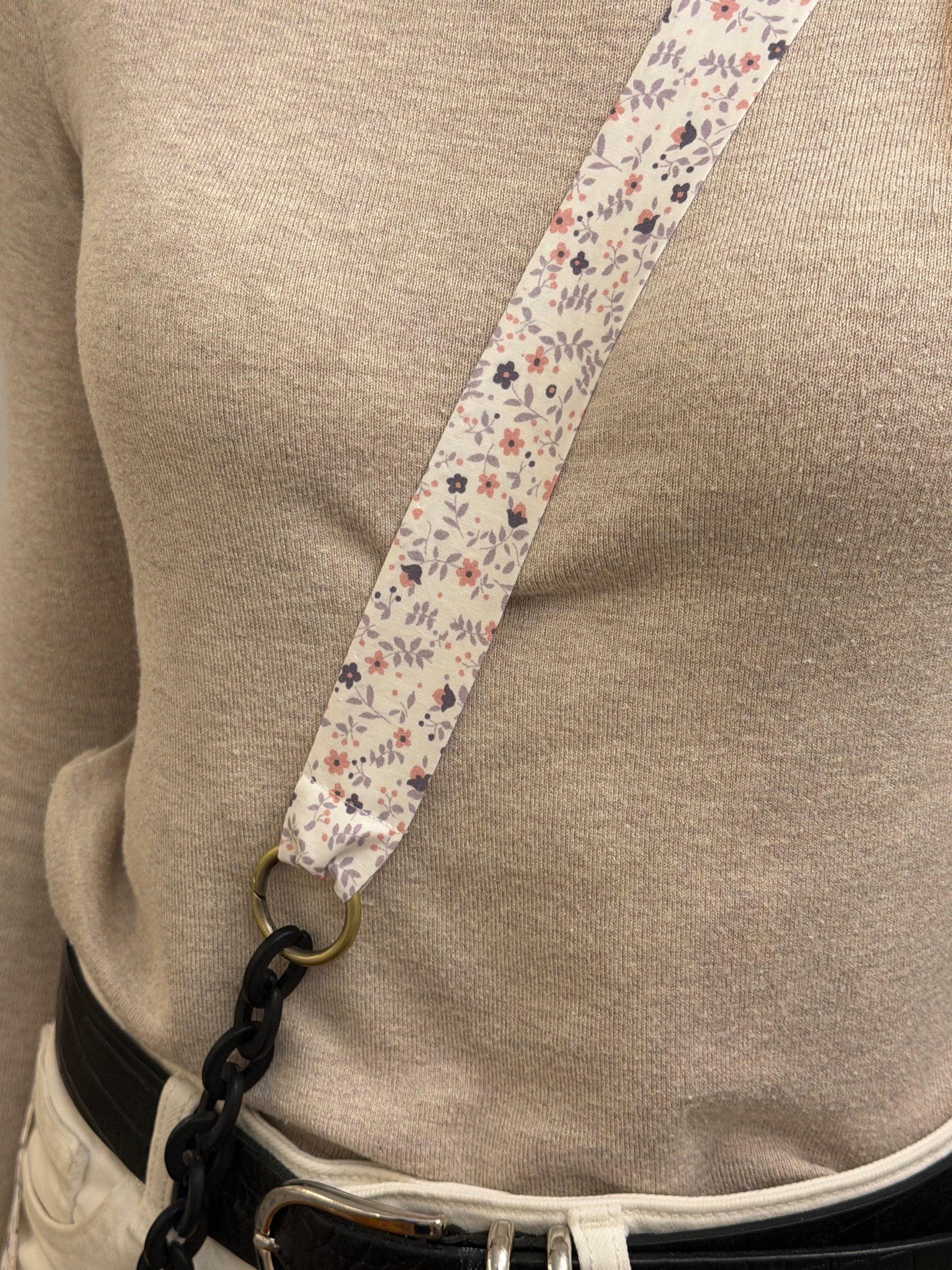 Cuelgamóvil con tela con flores y eslabones negros. Ajustable y con arandelas de acero inoxidable.