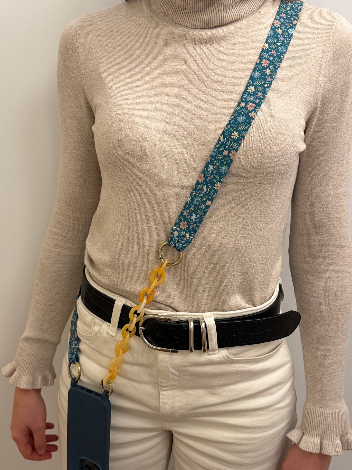 Cuelgamóvil con tela de color azul con flores y con eslabones en color beige. Ajustable y con arandelas de acero inoxidable.