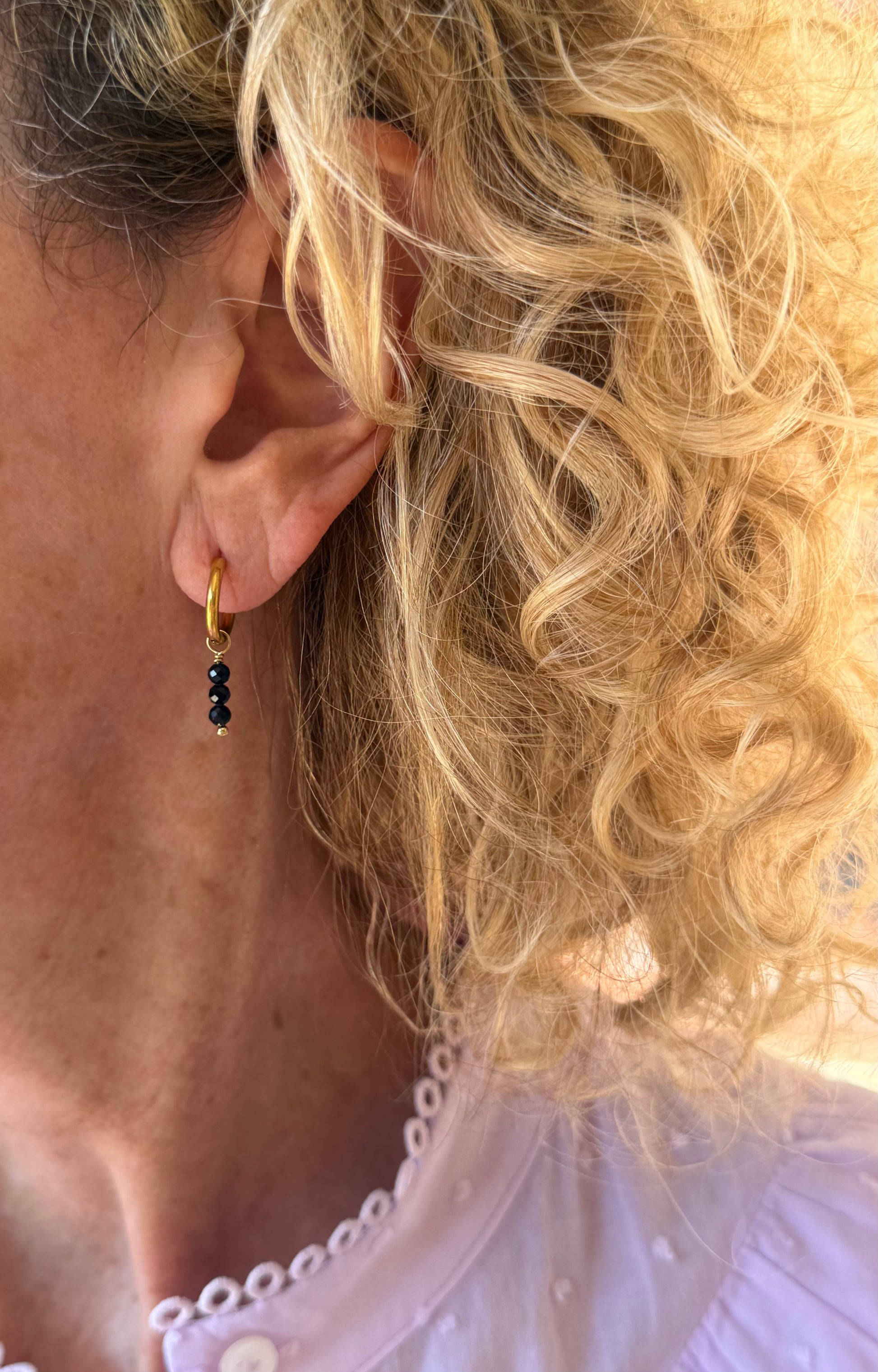 Pendientes de aro de acero inoxidable en color dorado con tres bolitas negras colgando. Estos pendientes son perfectos para elevar tus looks. 