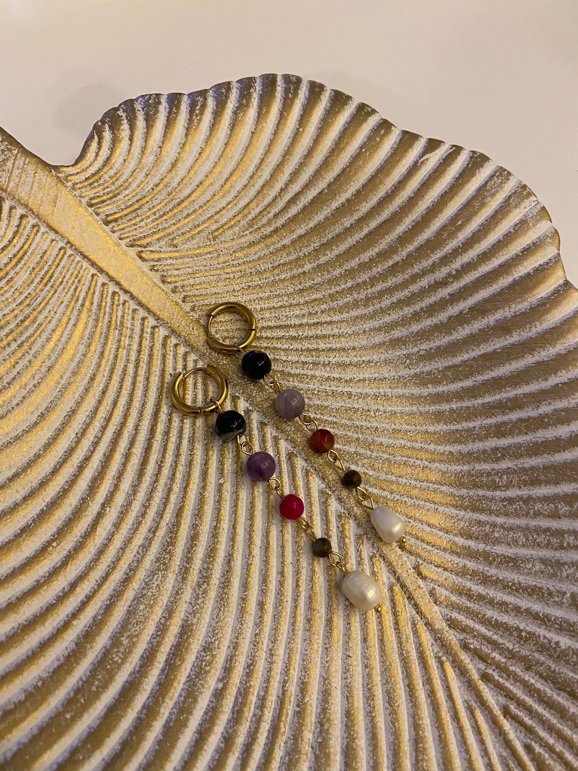 Pendientes de acero inoxidable en color dorado largos con piedras de colores y una perla. Estos pendientes son perfectos para elevar tus looks. 
