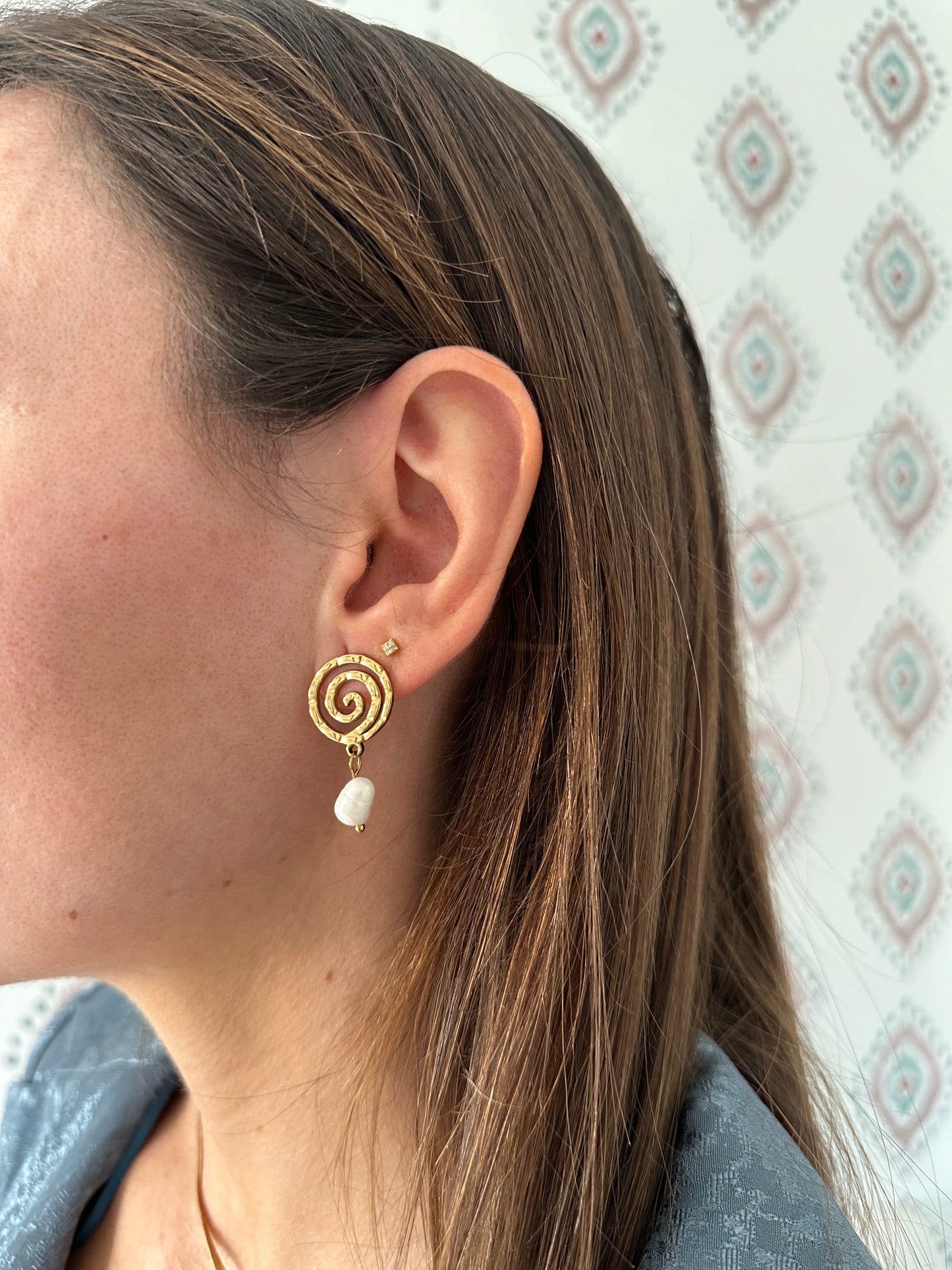 Pendientes de acero inoxidable en color plateado con espiral y una perla. Estos pendientes son perfectos para elevar tus looks. 