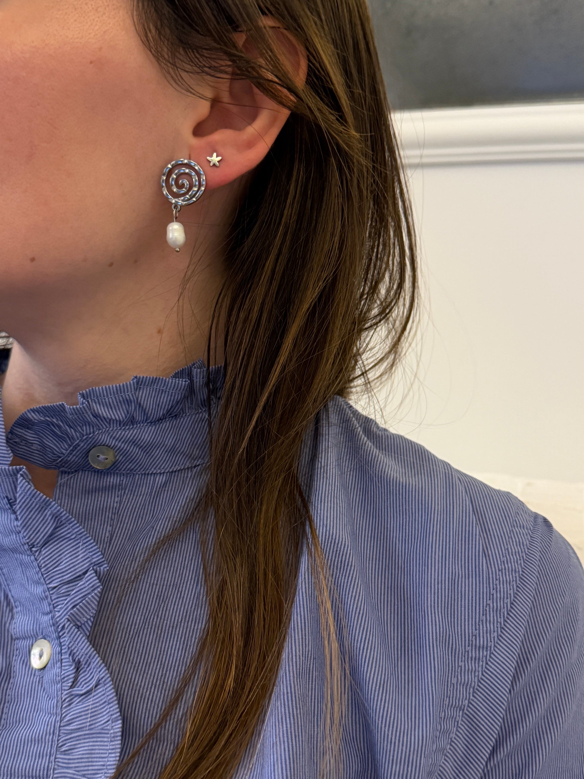 Pendientes de acero inoxidable en color plateado con espiral y una perla. Estos pendientes son perfectos para elevar tus looks. 