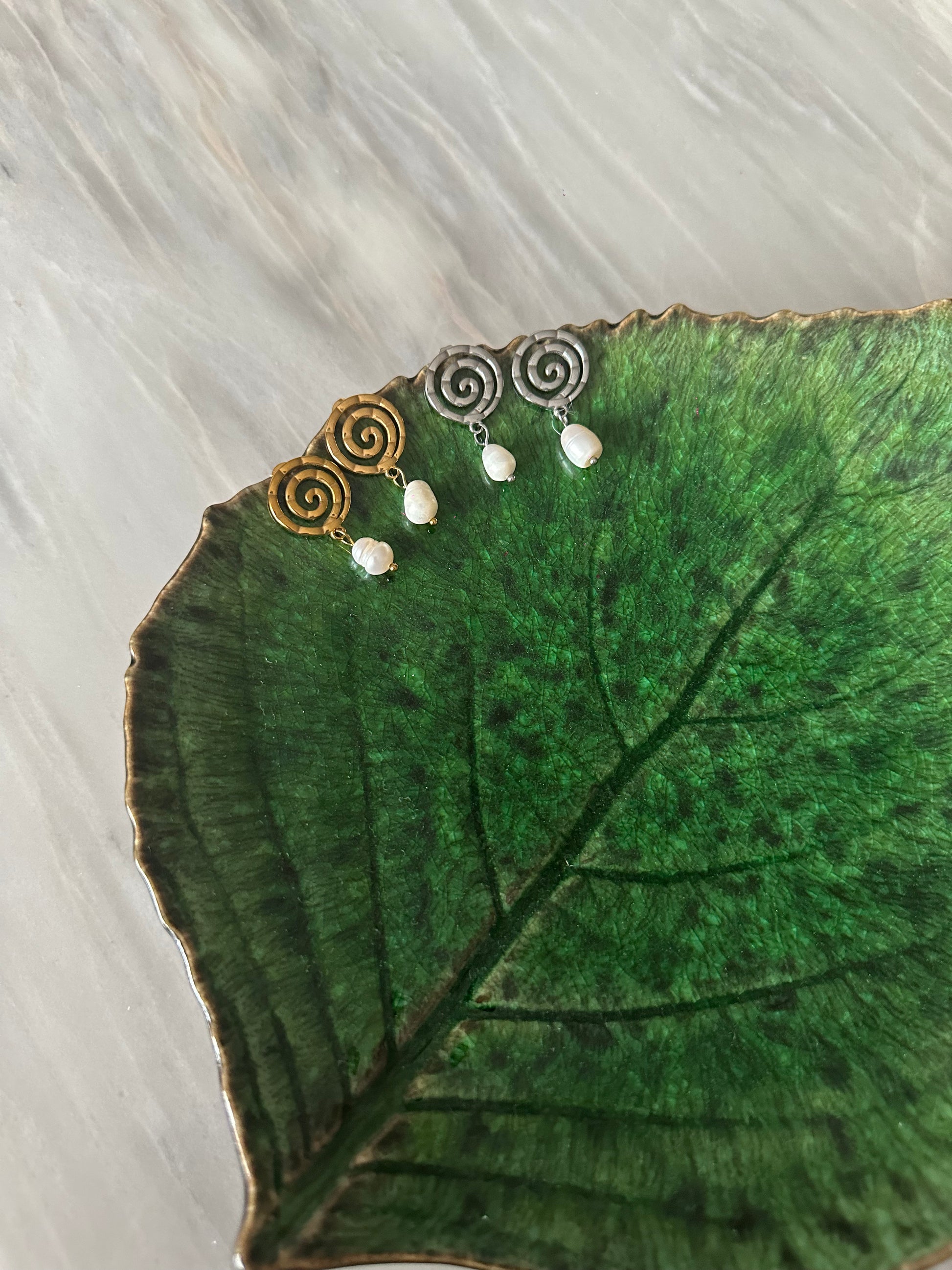 Pendientes de acero inoxidable en color plateado con espiral y una perla. Estos pendientes son perfectos para elevar tus looks. 