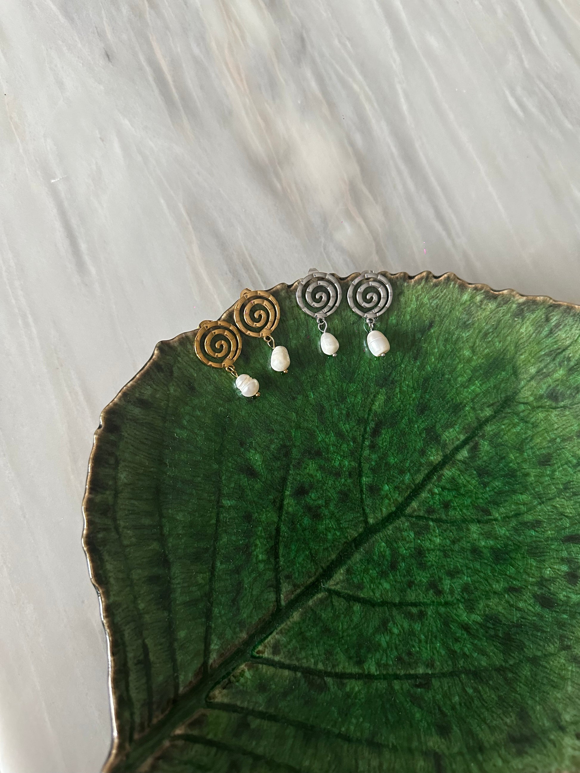 Pendientes de acero inoxidable en color plateado con espiral y una perla. Estos pendientes son perfectos para elevar tus looks. 