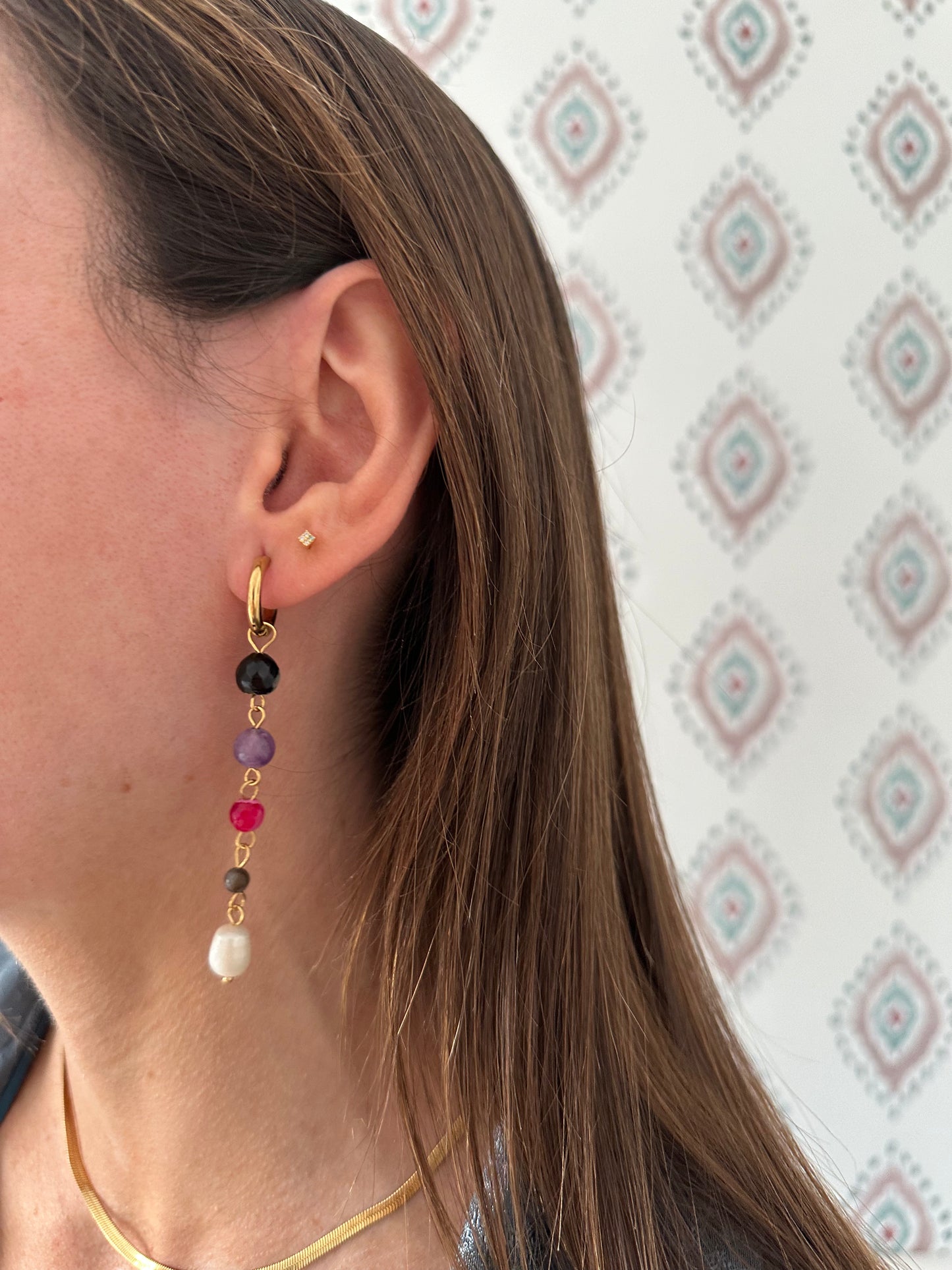 Pendientes de acero inoxidable en color dorado largos con piedras de colores y una perla. Estos pendientes son perfectos para elevar tus looks. 