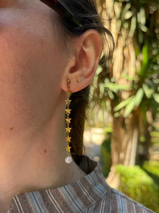 Pendientes de acero inoxidable largos con estrellas doradas y una perla. Estos pendientes son perfectos para elevar tus looks. 