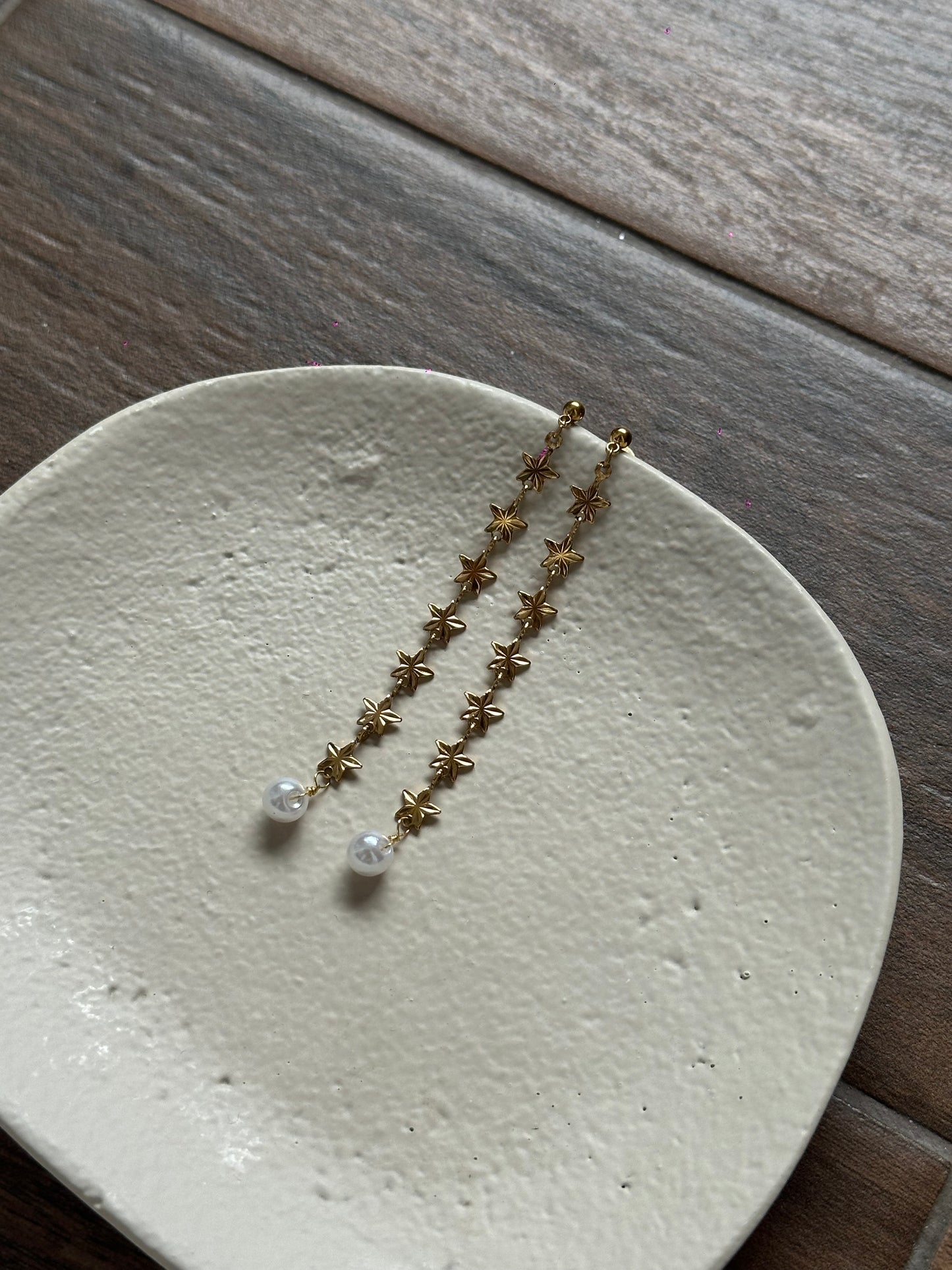 Pendientes de acero inoxidable largos con estrellas doradas y una perla. Estos pendientes son perfectos para elevar tus looks. 