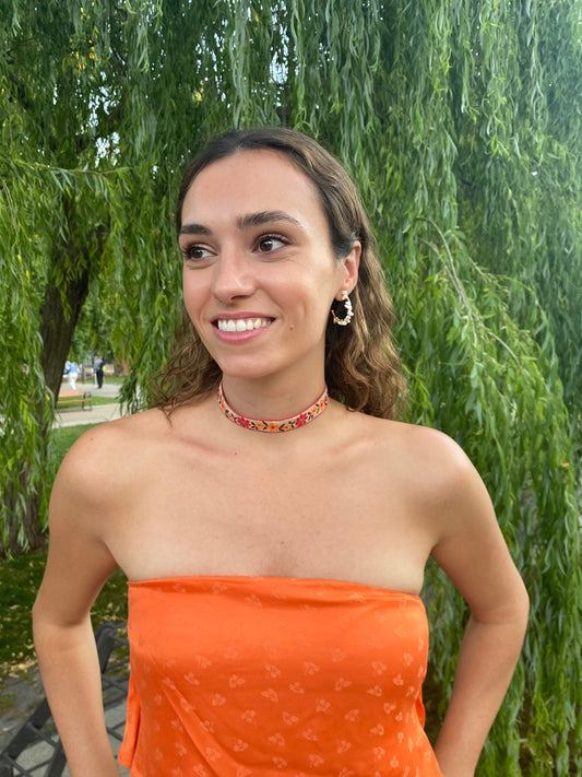 Modelo con choker de tela con flores bordadas, cierre ajustable y de acero inoxidable.